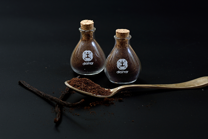 Vanilla powder in glass tube with grade a vanilla beans on a table